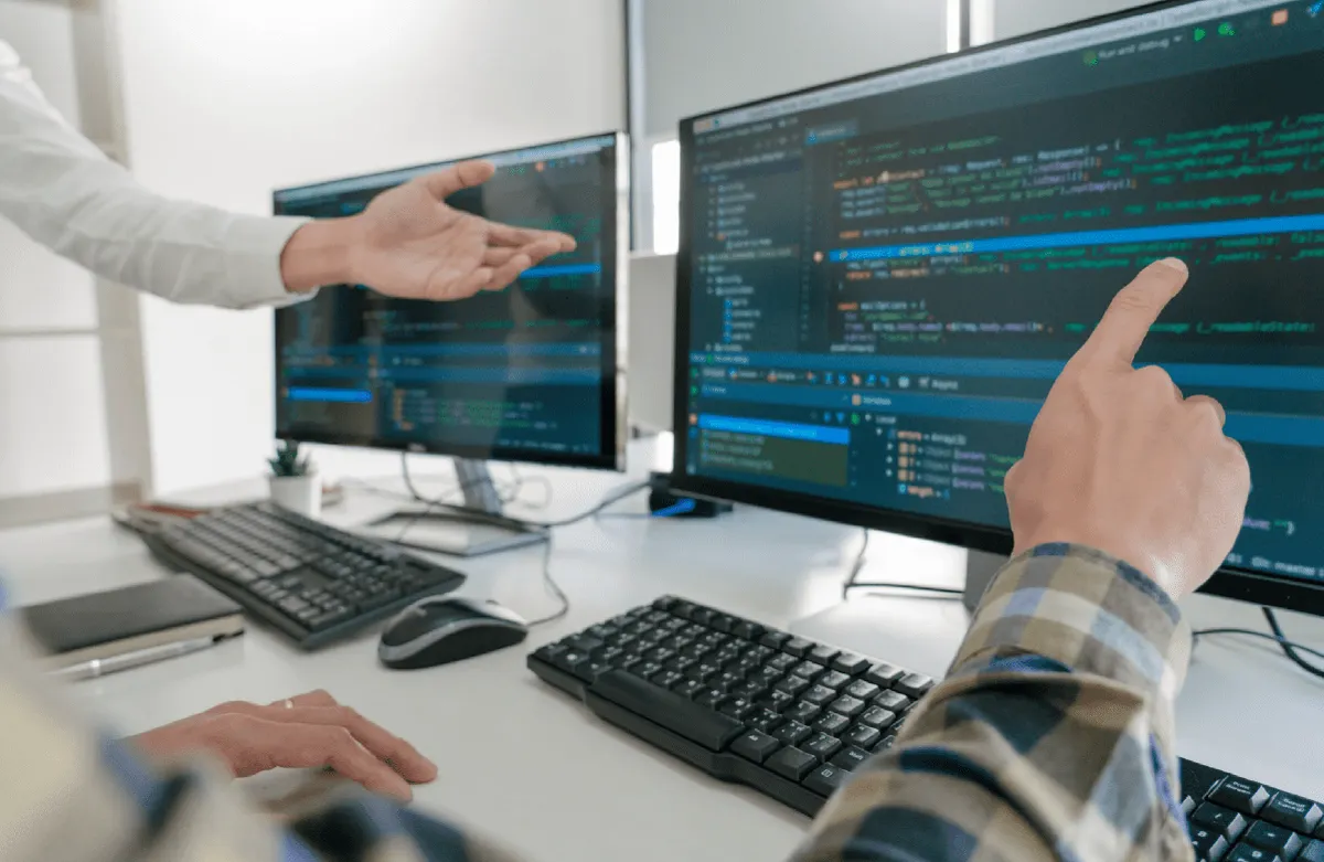Zwei Entwickler besprechen Code an zwei Monitoren